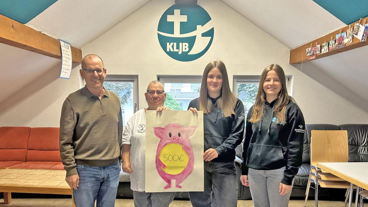 Anette Mayer und Rebekka Müller halten ein gemaltes Bild eines Sparschwein mit dem Schriftzug 500 € in die Kamera.