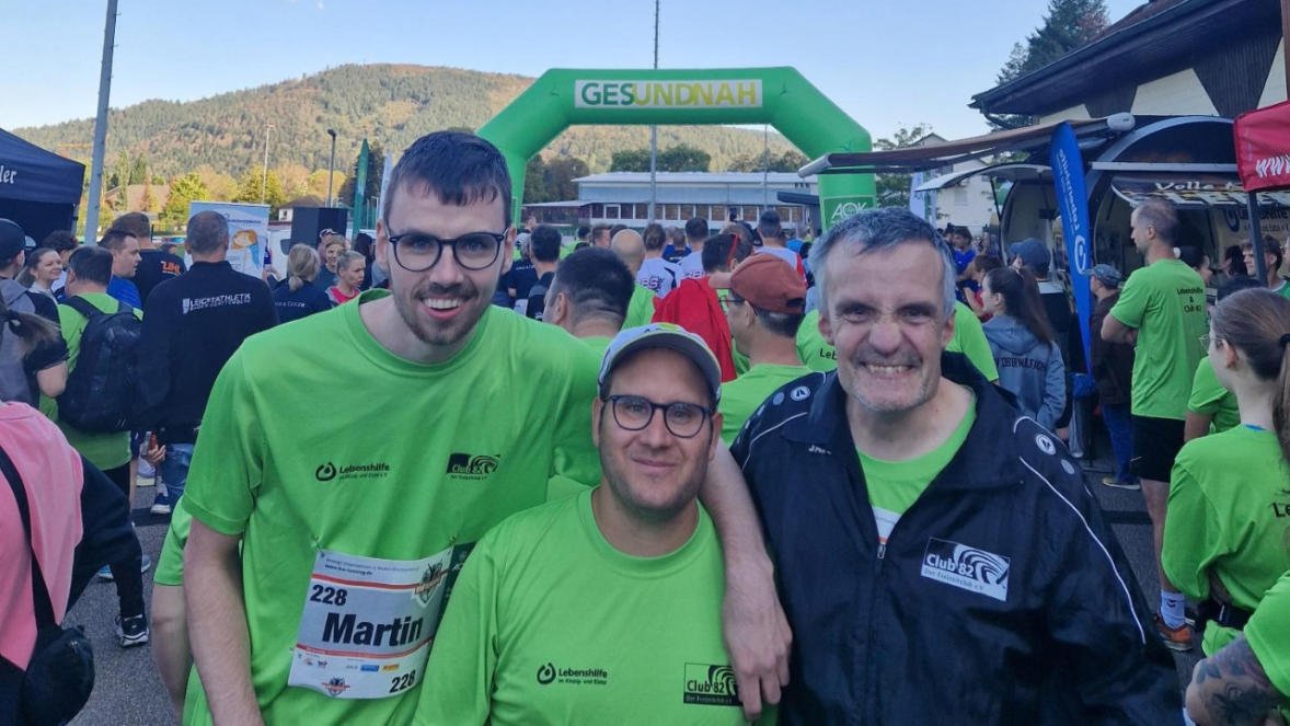 3 Personen stehen bei einer Sportveranstaltung im Zielbereich. 