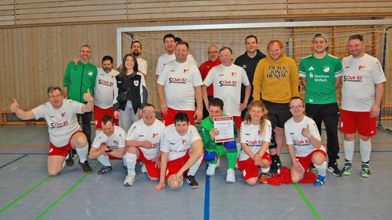 Fuusballteam des Club 82 steht vor einem Tor und jubelt.