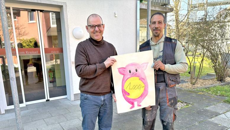 Spender Fadi Morra und Geschäftsführer Helmut Walther halten ein Plakat mit der Aufschrift 1.000 € in der Hand