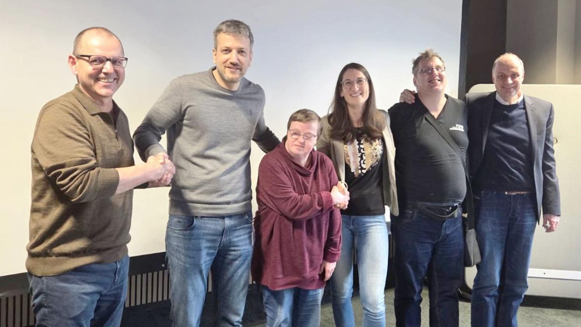 Personen von BENZ Tooling und Club 82 stehen eng nebeneinander und lachen.